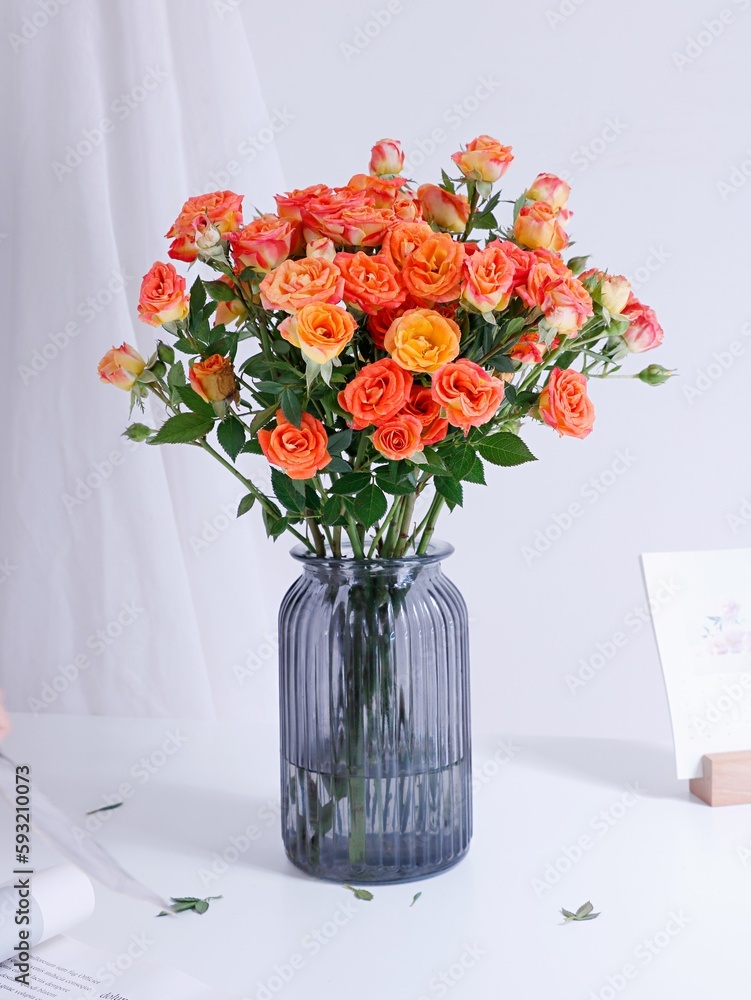 Vertical shot of a beautiful bouquet of roses in a blue glass vase on a white table