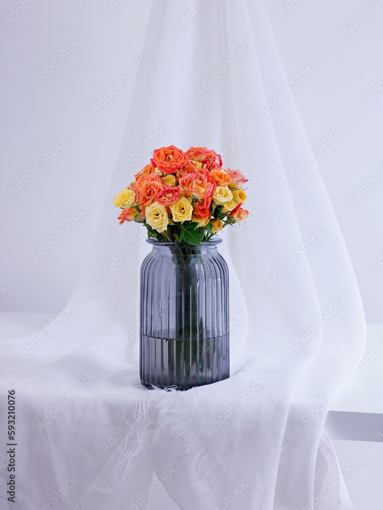 Closeup of a colorful rose bouquet in black transparent vase on a minimalistic decor background