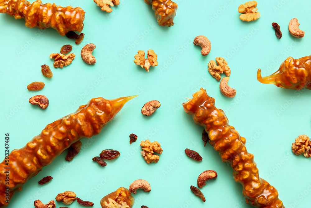 Composition with tasty churchkhela, nuts and raisin on color background