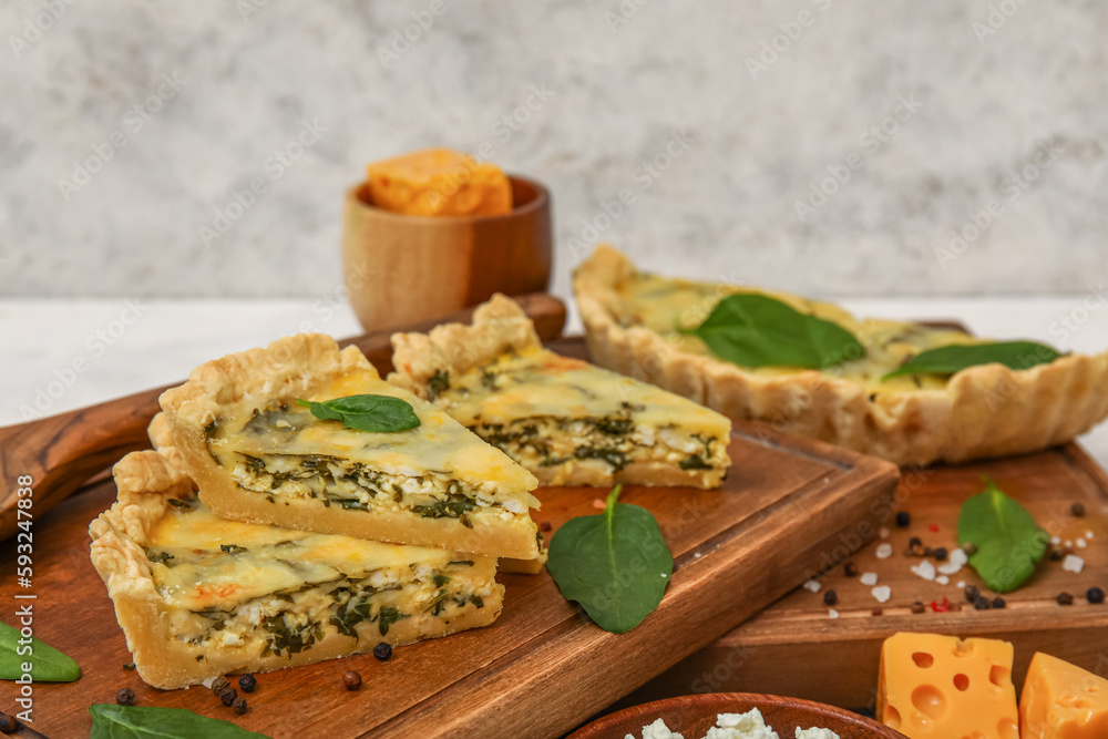 Board with pieces of delicious quiche on white table