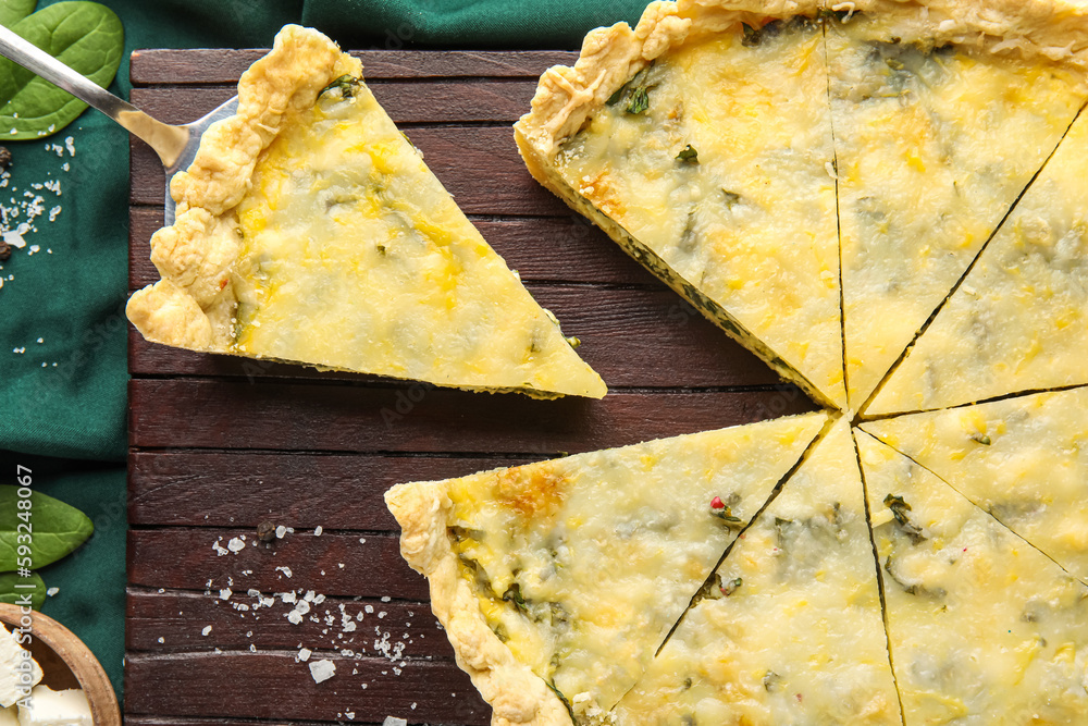 Board with pieces of delicious quiche on beige background