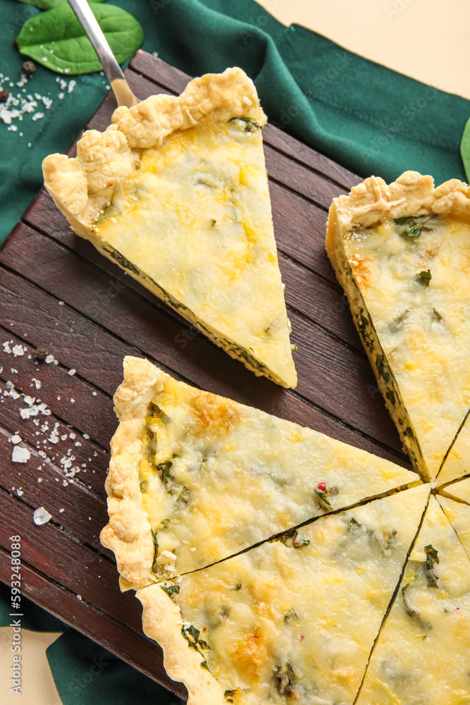 Board with pieces of delicious quiche on beige background