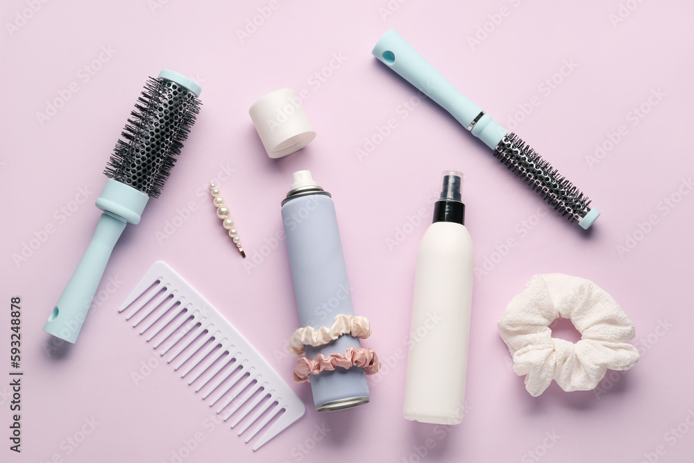 Bottles of hair sprays, brushes, comb and accessories on color background