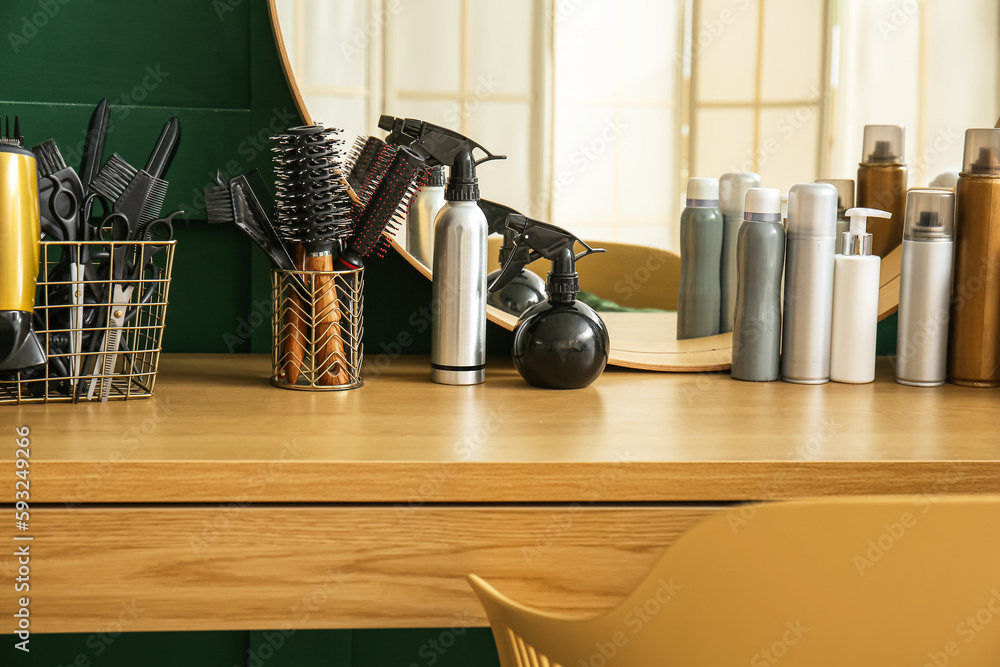 Different hair sprays and accessories on table in beauty salon