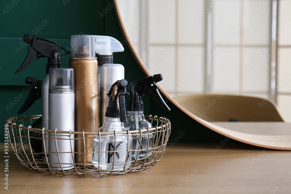 Basket with different hair sprays on table in beauty salon