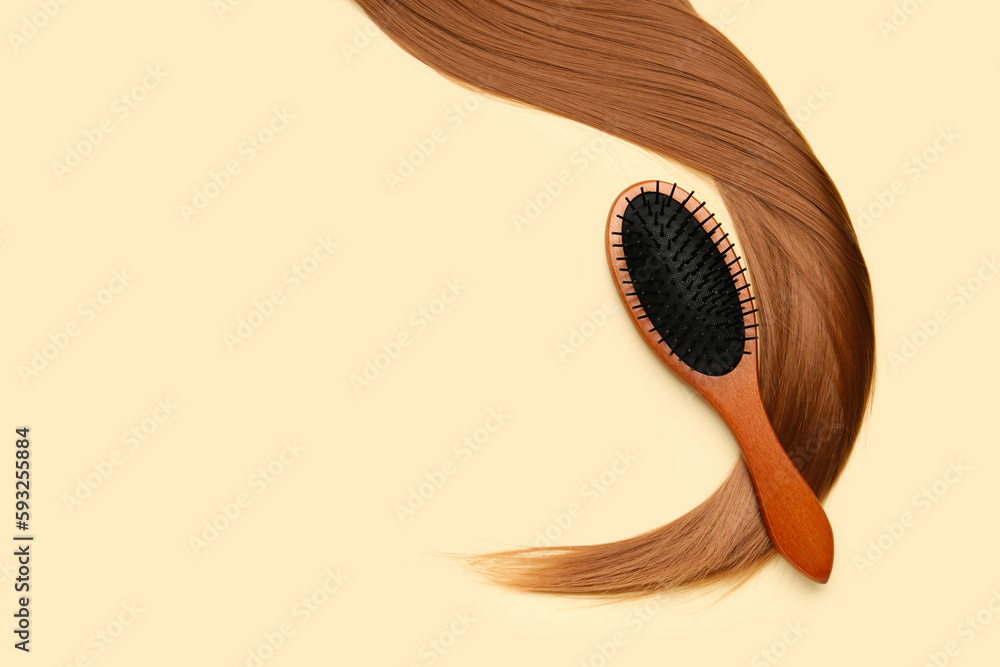 Hair strand with brush on beige background