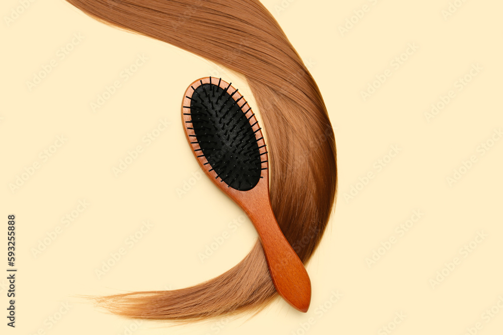 Hair strand with brush on beige background