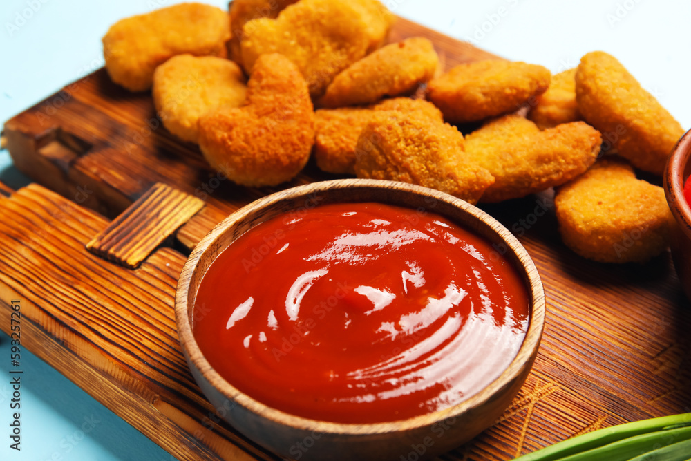 Bowl with tasty ketchup on blue background, closeup