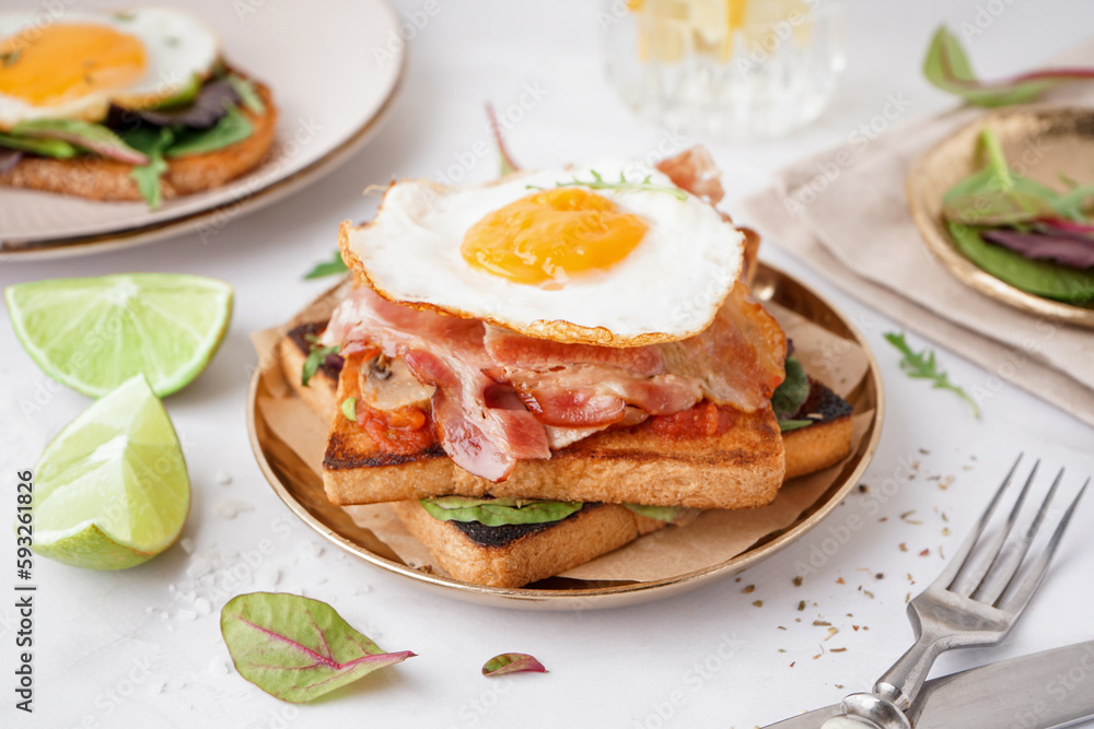 Delicious sandwich with fried egg and bacon on light background