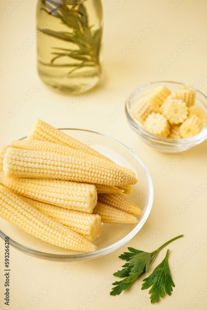 Plate with cut and whole canned baby corn cobs on yellow background