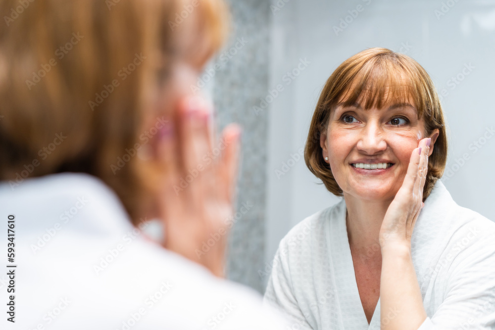 Caucasian senior woman wash and clean face with facial foam and water. 