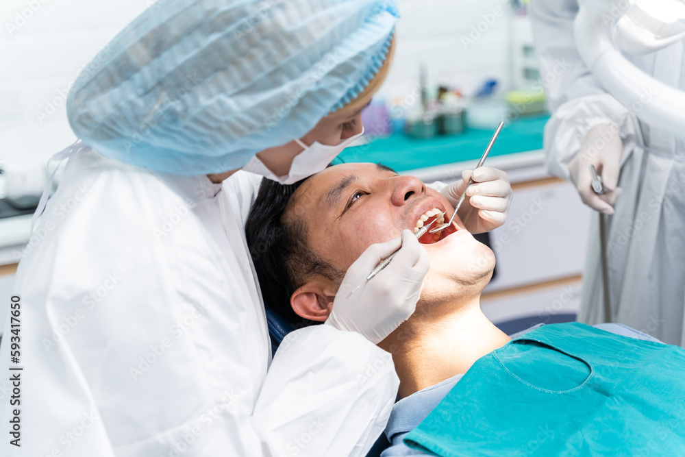 Caucasian dentist examine tooth for young man patient at dental clinic. 