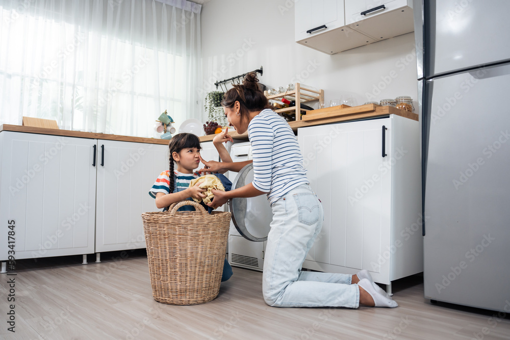 Caucasian beautiful mother teaching young daughter wash dirty clothes. 