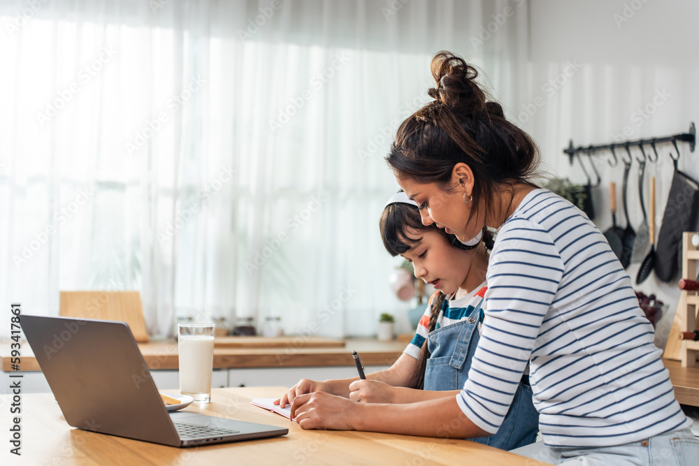 Caucasian young girl kid learning online class at home with mother. 