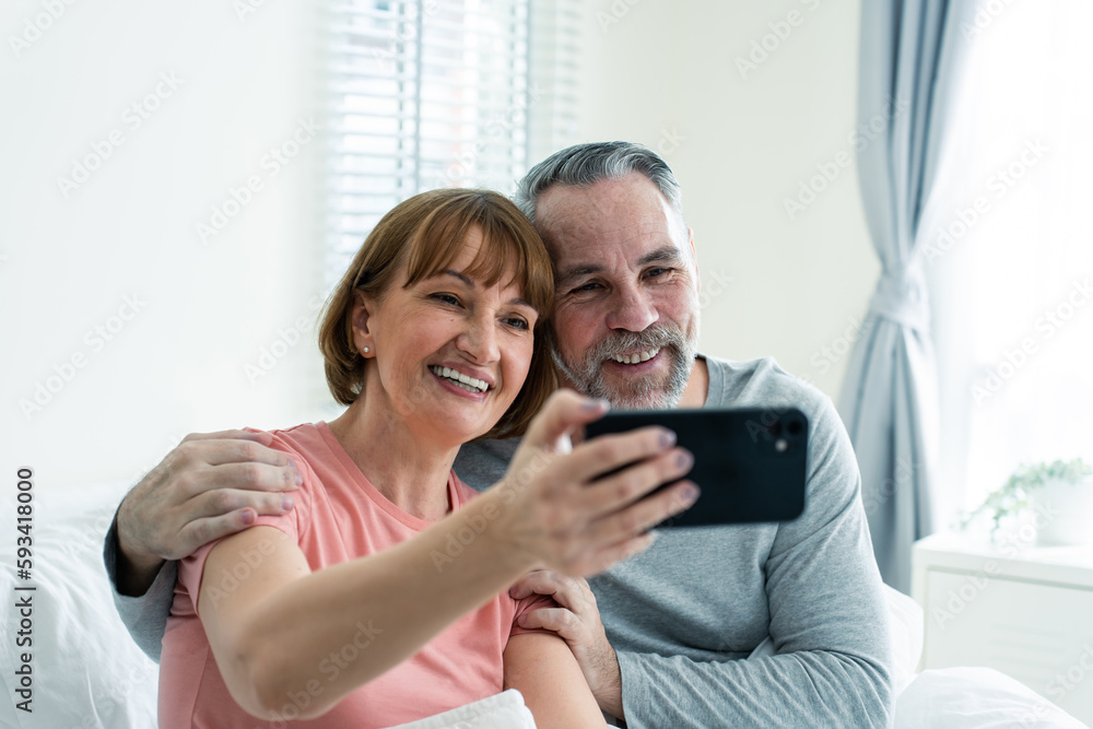 Caucasian senior couple video call with family in bedroom in house. 