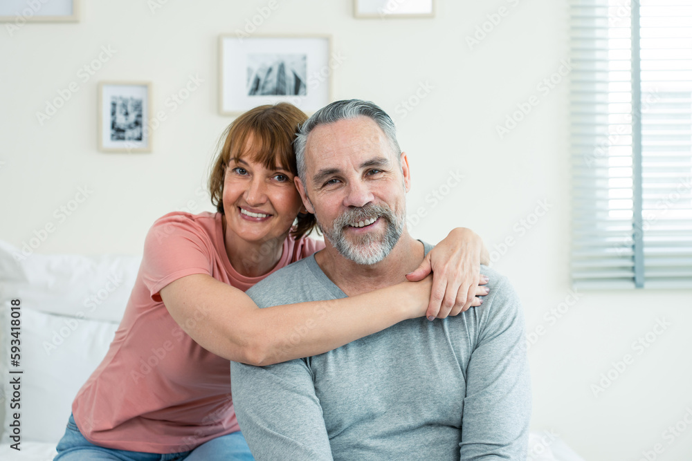 Portrait of Caucasian senior elderly couple sitting on bed in bedroom. 