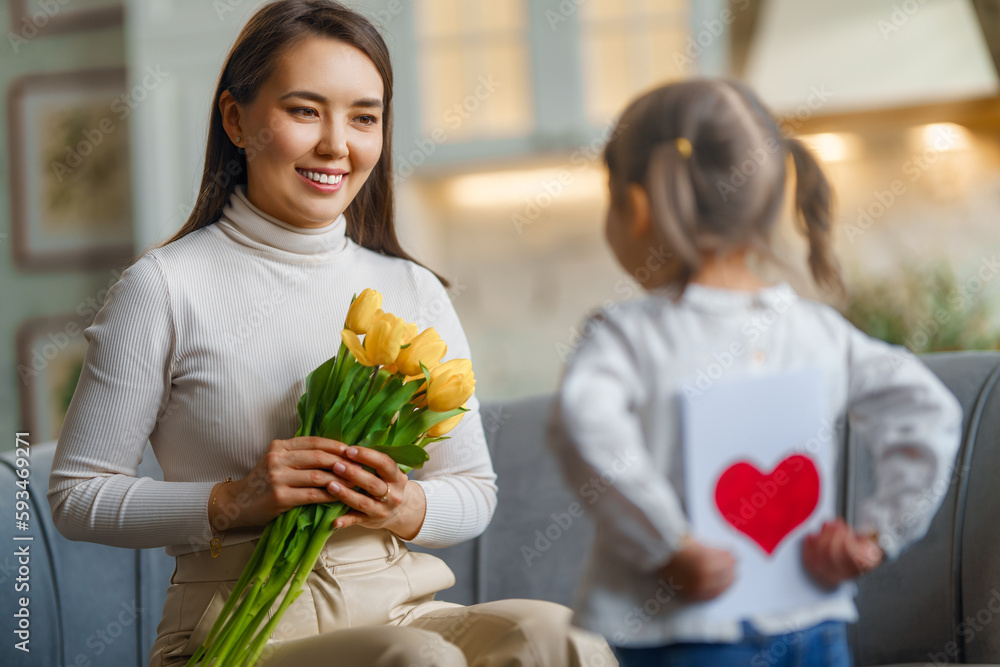 Daughter giving mother bouquet of flowers.