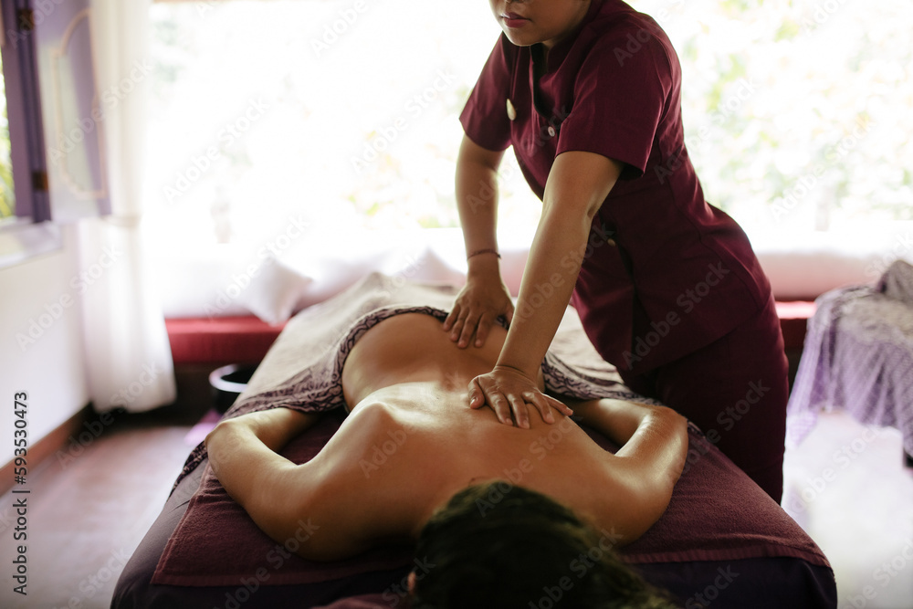 Massage therapist hands massaging back of a woman