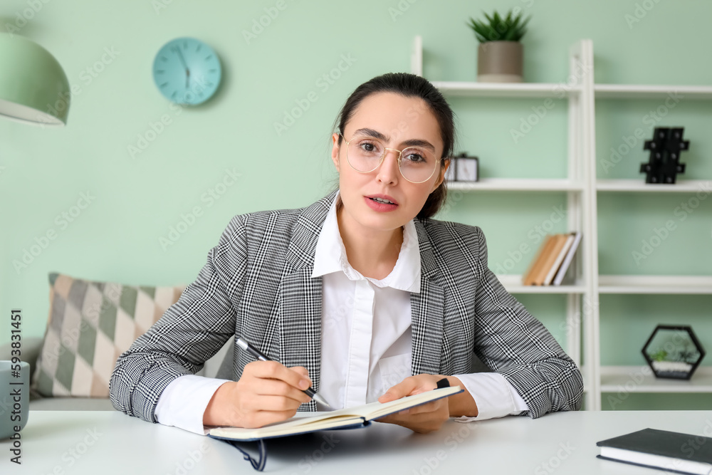 Female tutor with notebook giving online lesson at home