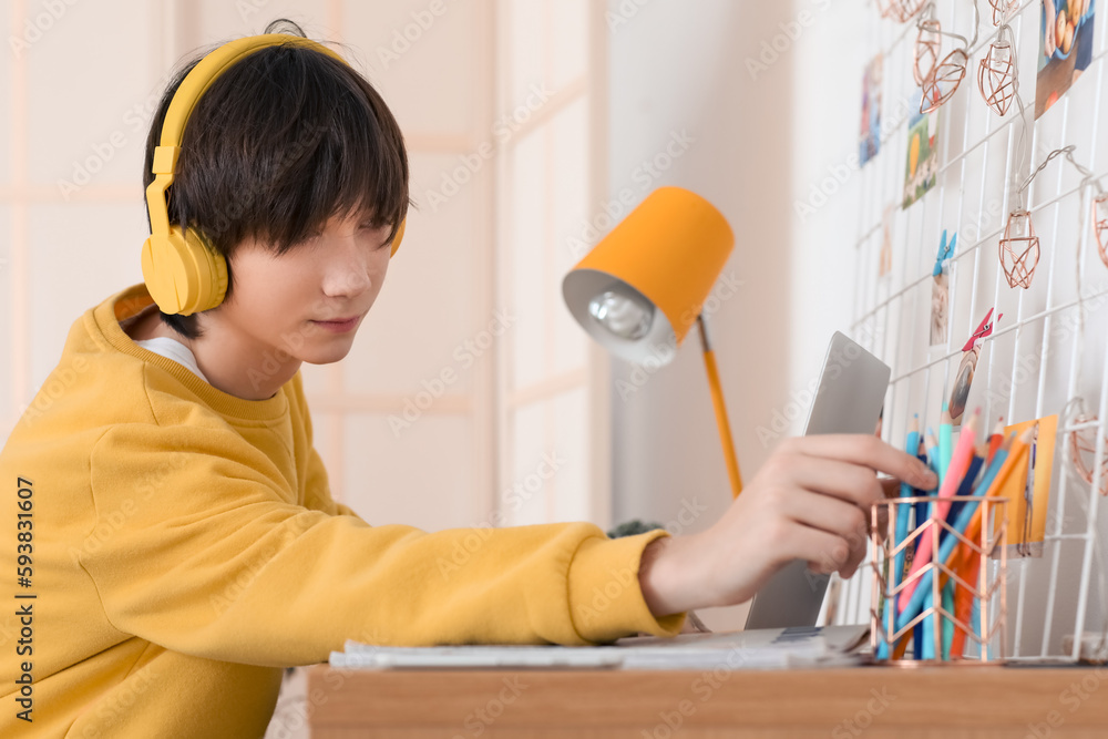 Male student in headphones studying online at home