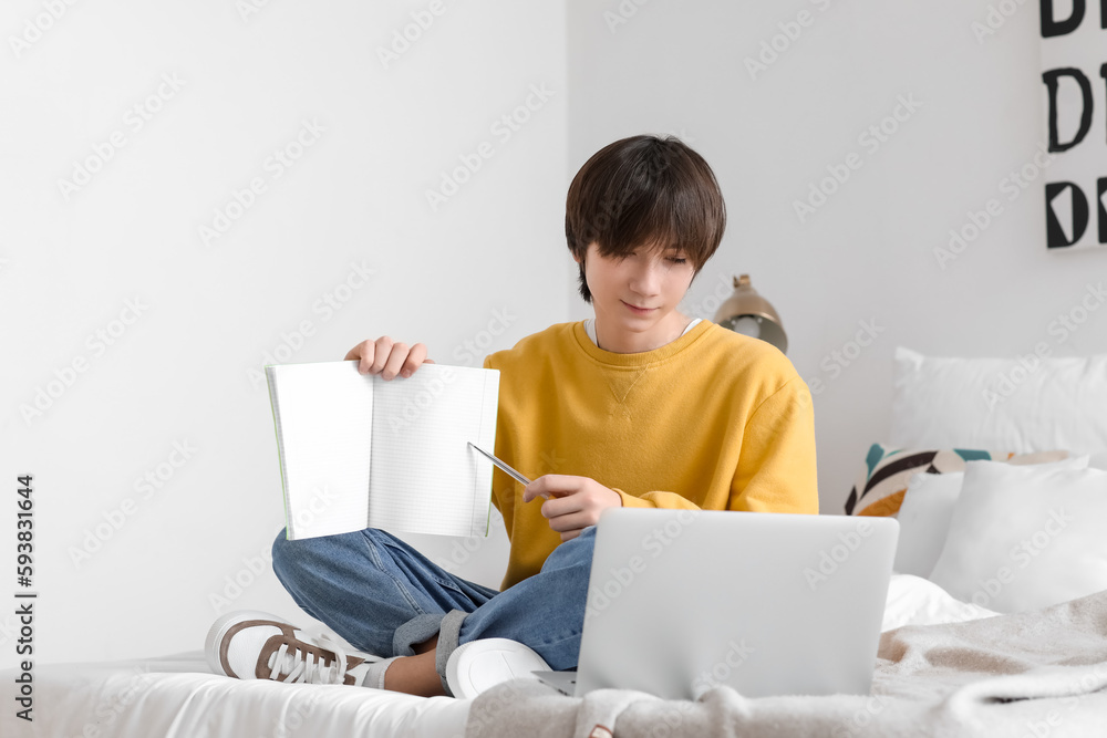 Male student with notebook studying online at home