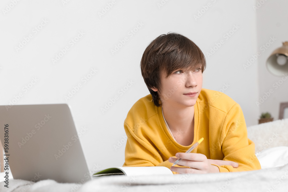 Male student with laptop studying online in bedroom