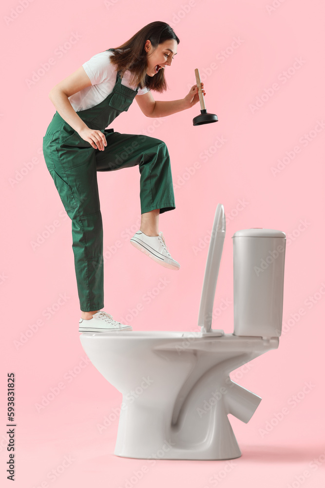 Funny female plumber with plunger and toilet bowl on pink background