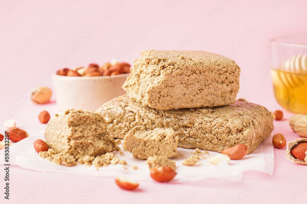 Tasty halva and peanuts on pink background