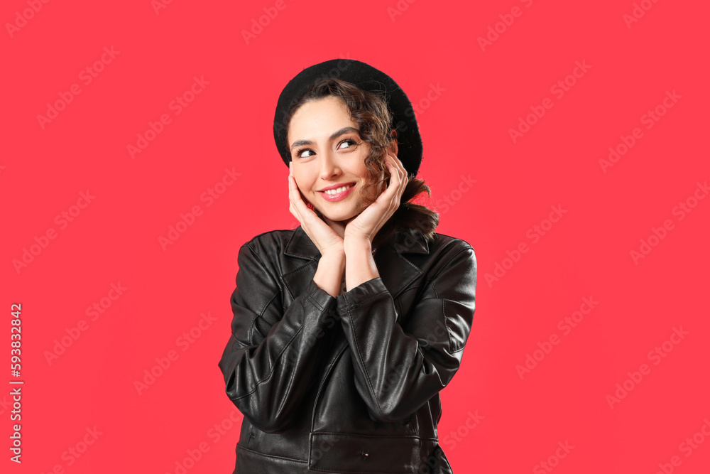 Stylish young woman in leather jacket on red background