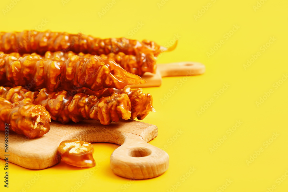 Wooden boards with tasty churchkhela on yellow background, closeup