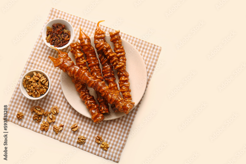 Plate with tasty churchkhela, raisin and walnuts on light background