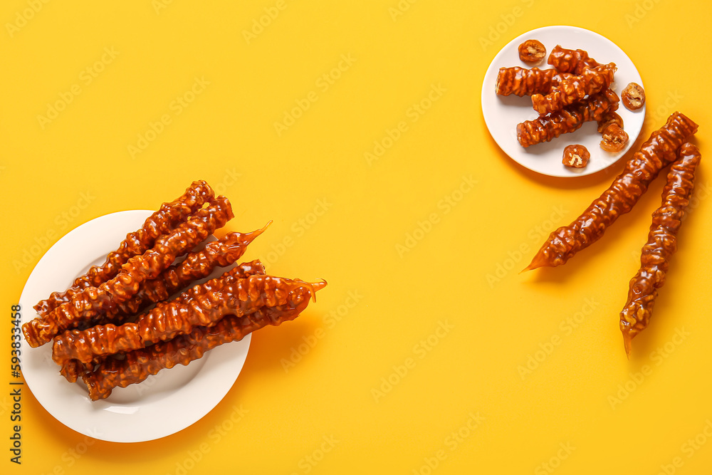 Plates with tasty churchkhela on yellow background