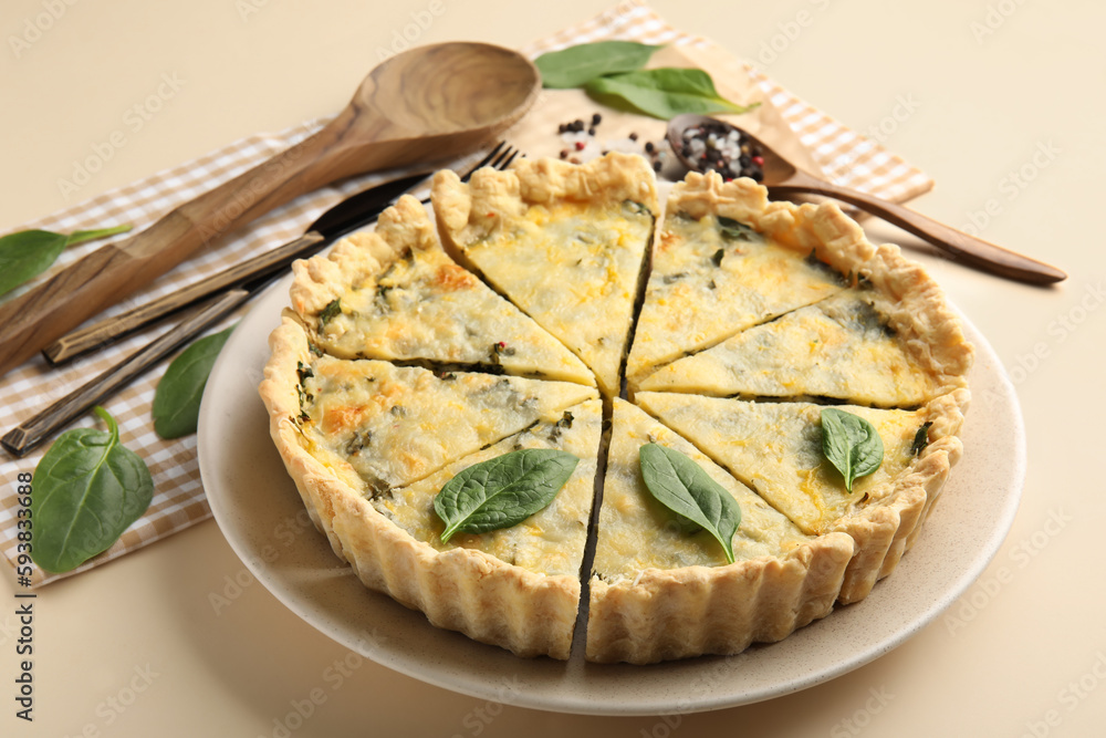 Plate with pieces of delicious quiche on beige background