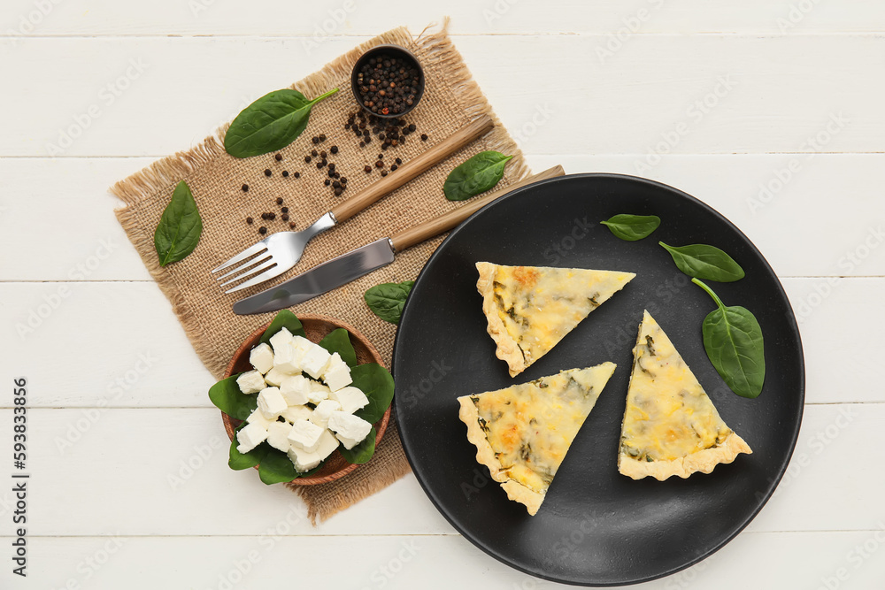 Plate with pieces of delicious quiche and feta cheese on white wooden background