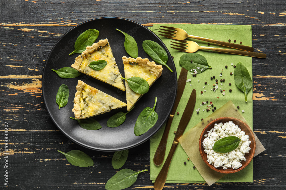 Plate with pieces of delicious quiche on black wooden background