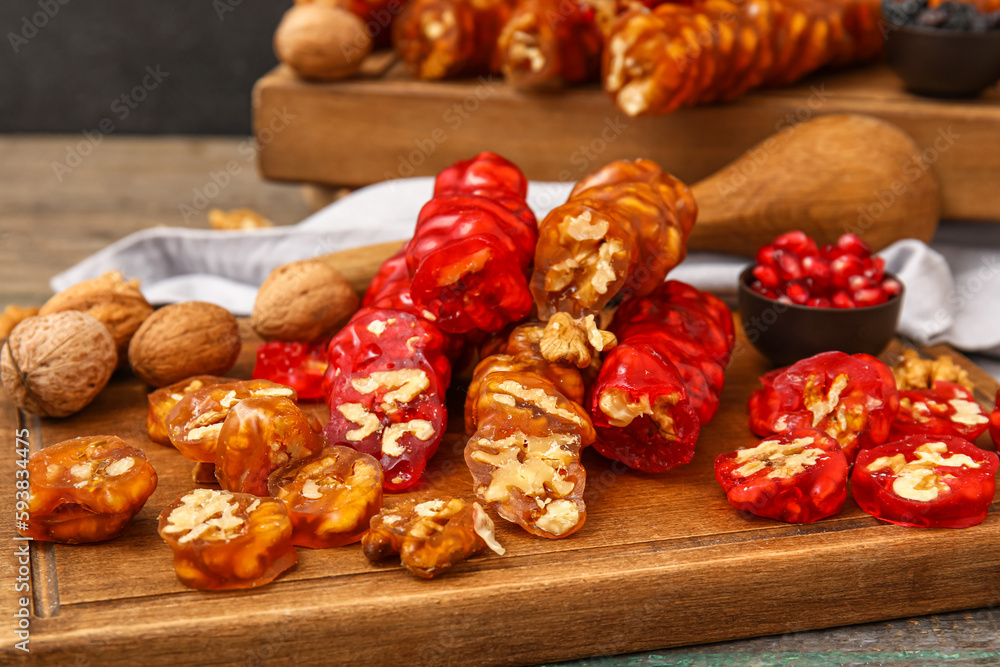 Board with delicious churchkhela and walnuts on wooden table