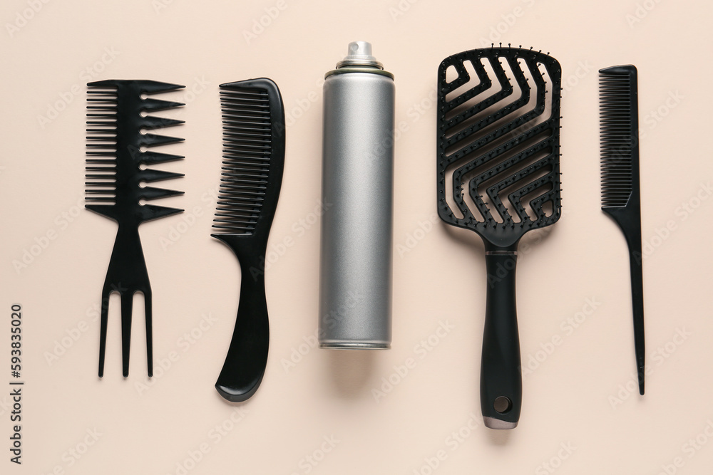 Bottle of hair spray, brush and combs on color background