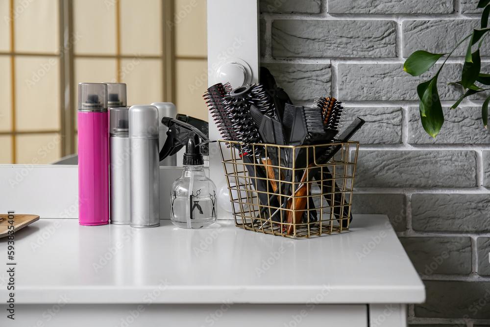 Different hair sprays and accessories on table in beauty salon