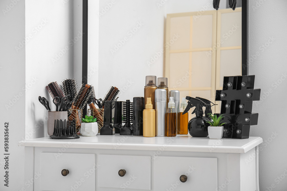 Different hair sprays and accessories on table in beauty salon