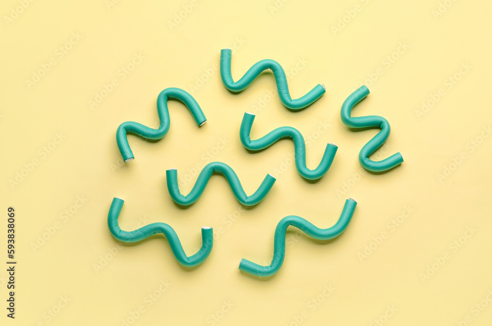 Hair curlers on yellow background