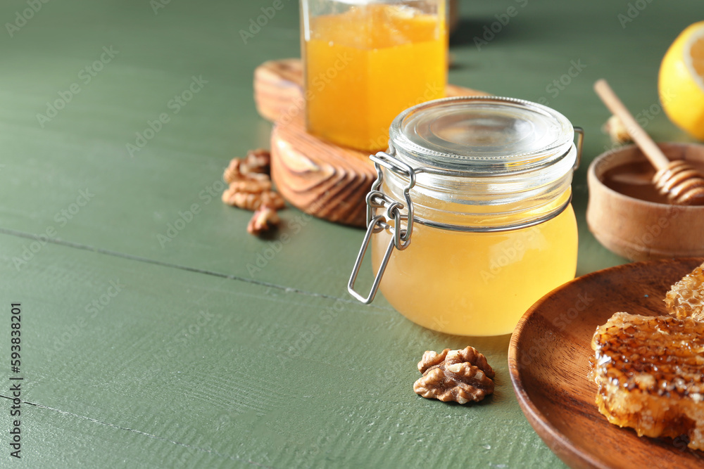 Jars of sweet honey on green wooden background