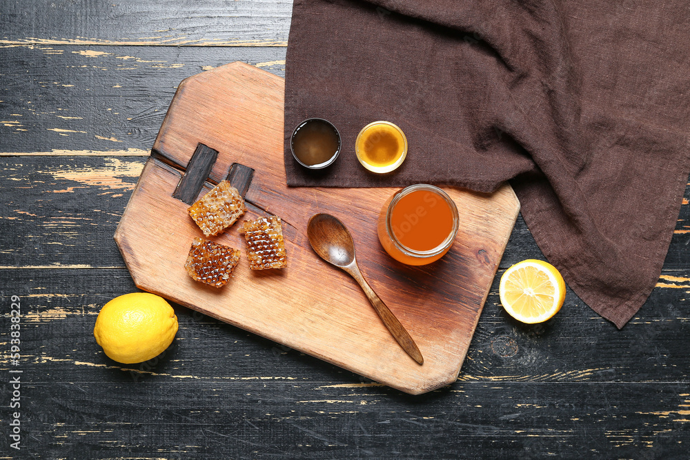 Composition with sweet honey, combs and lemon on dark wooden background