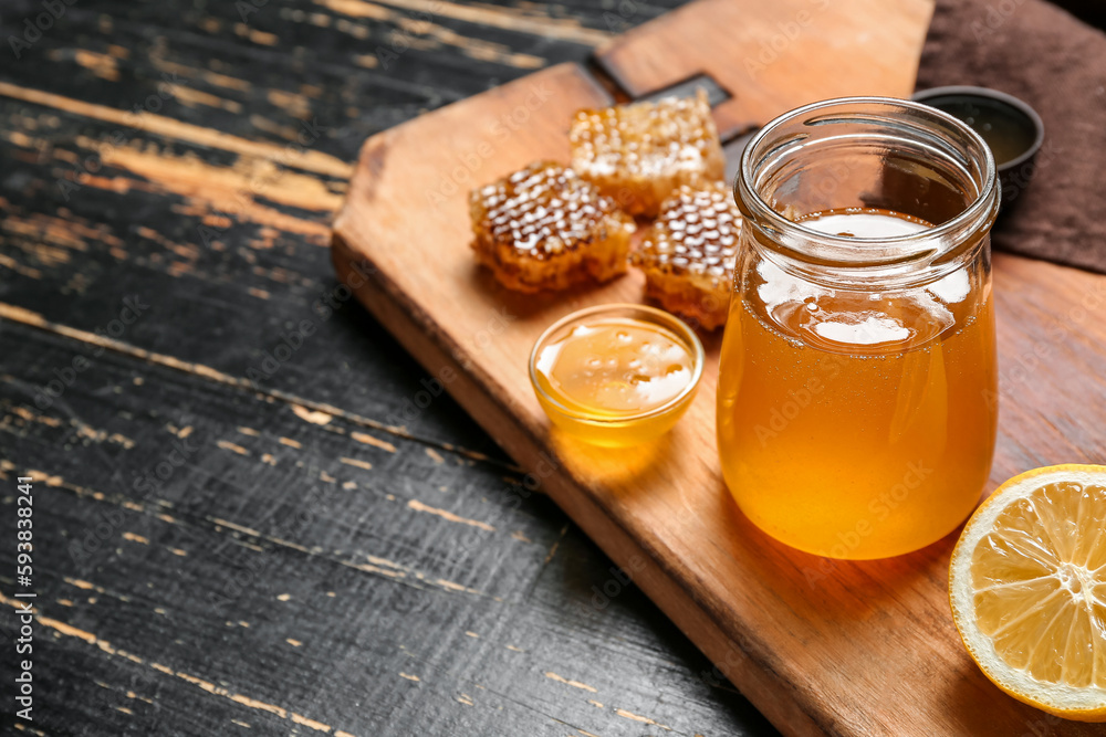 Jar with sweet honey on dark wooden background