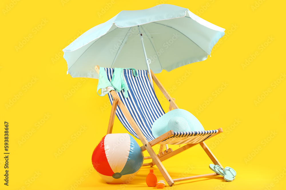 Deck chair, blue umbrella and beach accessories on blue background