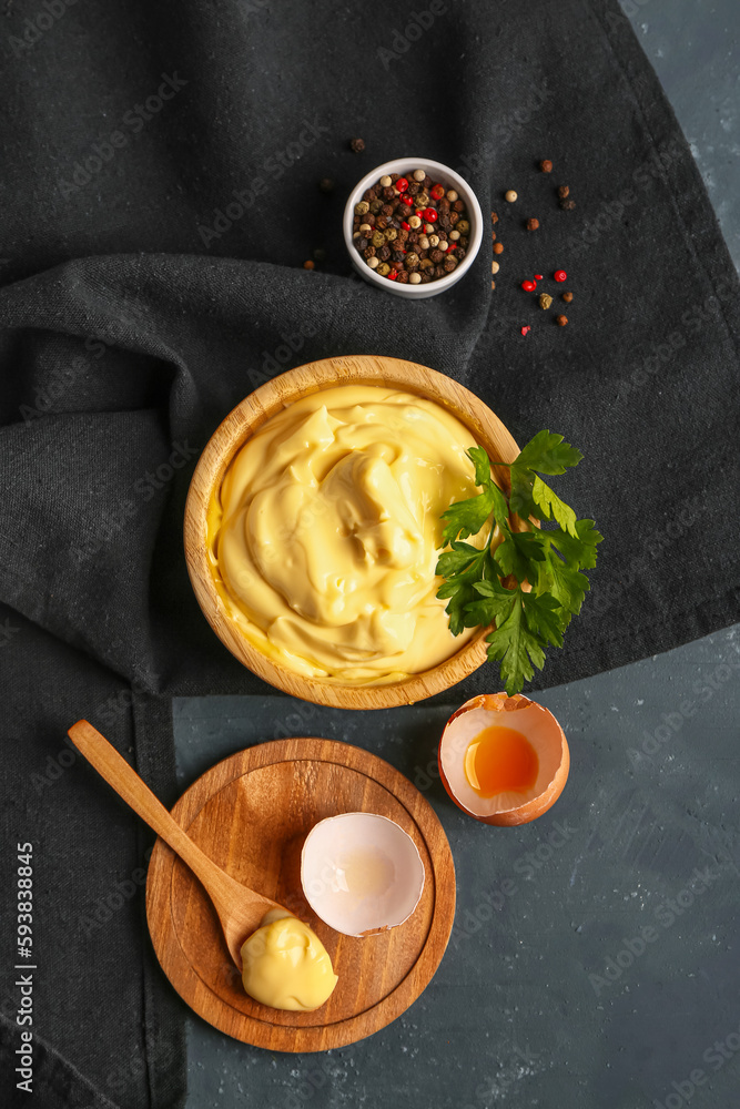 Bowl with tasty mayonnaise sauce on green background