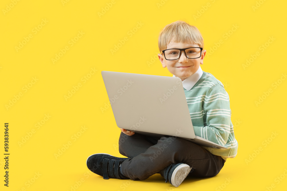 Funny little businessman with laptop sitting on yellow background