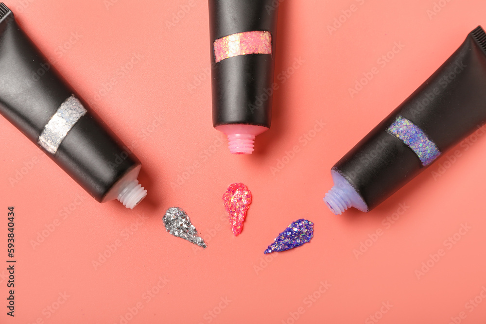 Tubes of glitter with strokes on pink background, closeup