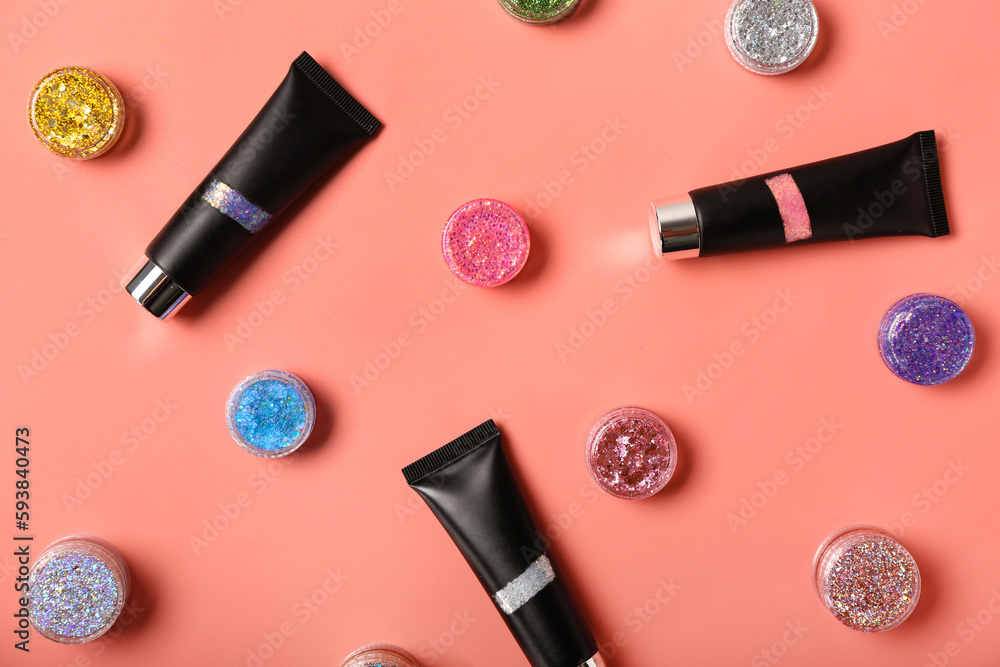 Tubes with jars of glitter on pink background