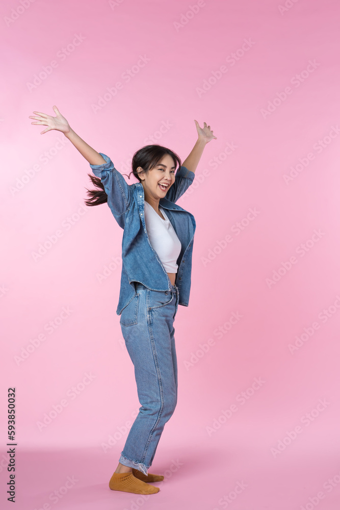 Elegant young Asian woman raises her arm and leg in a studio shot, expressing happiness and success 