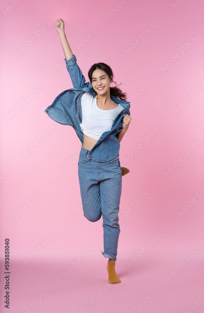 Elegant young Asian woman raises her arm and leg in a studio shot, expressing happiness and success 